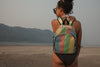 TORRAIN Recycled Bags, Designed in Portland, Oregon : Small backpack in multi color pattern worn on a women in a bathing suit standing on a beach.